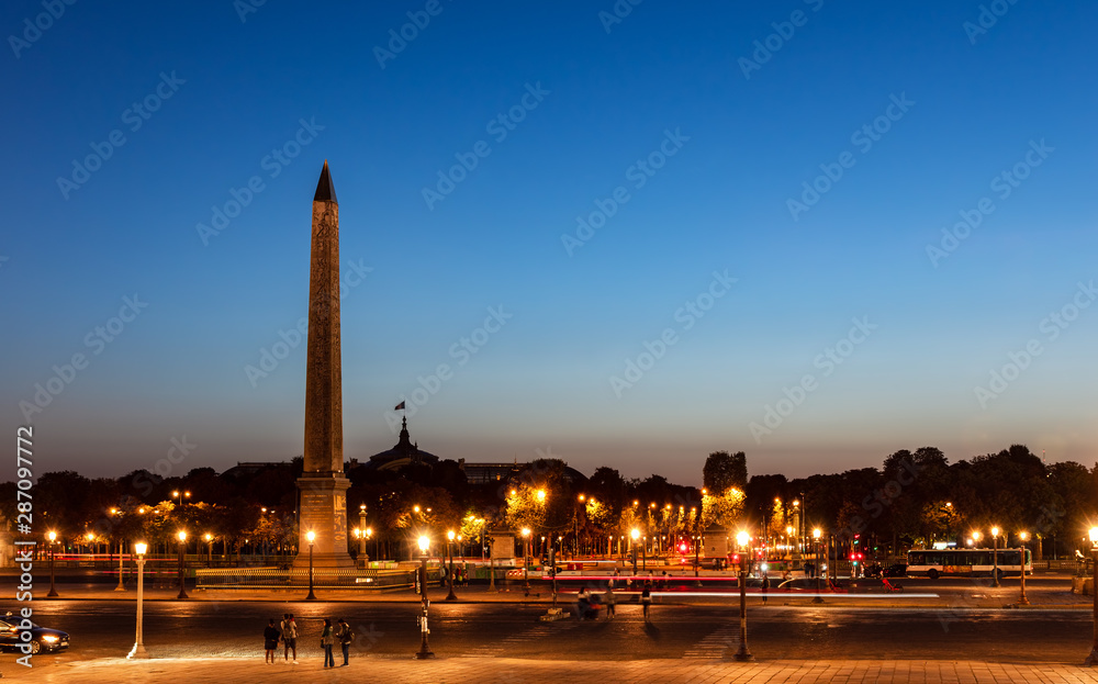 Traffic on Place de la Concorde at night with Obelisk of Luxor and Grand Palais in background - Paris, France