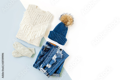 Blue winter hat with jeans, sweater and mittens on white background. Women's stylish autumn or winter clothes. Trendy clothes collage. Flat lay, top view.