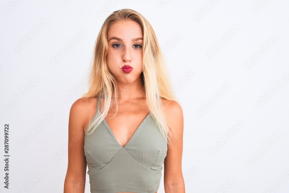 Young beautiful woman wearing casual green t-shirt standing over isolated white background puffing cheeks with funny face. Mouth inflated with air, crazy expression. Young beautiful woman wearing casual green t-shirt standing over isolated white background puffing cheeks with funny face. Mouth inflated with air, crazy expression.