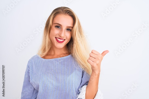 Young beautiful woman wearing elegant blue t-shirt standing over isolated white background happy with big smile doing ok sign, thumb up with fingers, excellent sign