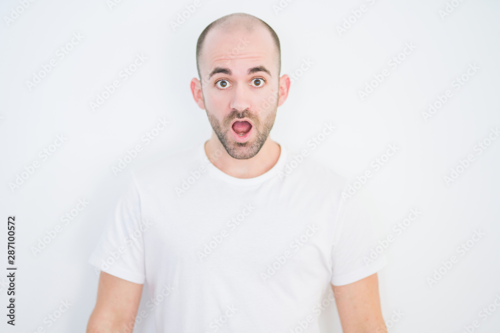 Young bald man over white isolated background afraid and shocked with surprise expression, fear and excited face.