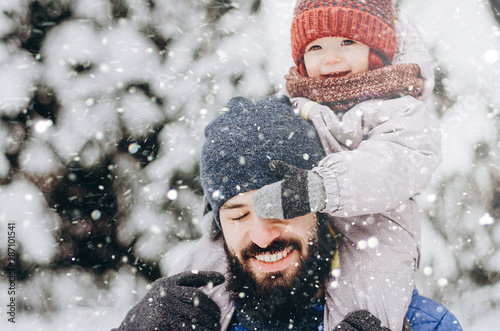 Happy loving family! Father and his baby are playing and hugging outdoors. Cute little child and daddy on snowy winter walk in nature. Concept of frost winter season.