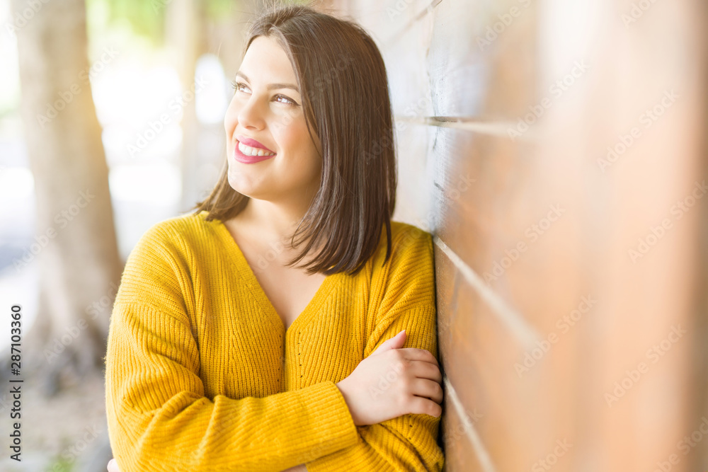 Beautiful young woman smiling confident and cheerful leaning on wooden wall, walking on the street of the city on a sunny day Beautiful young woman smiling confident and cheerful leaning on wooden wall, walking on the street of the city on a sunny day