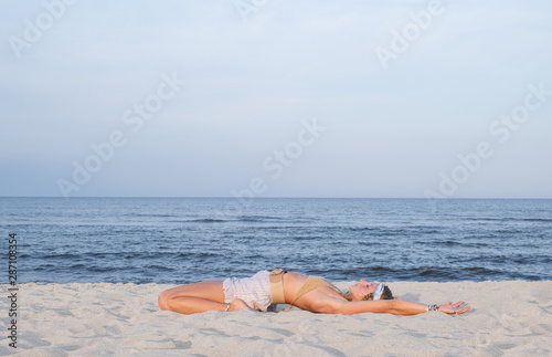 Young woman practicing yoga on the beach. Supta Virasana photo