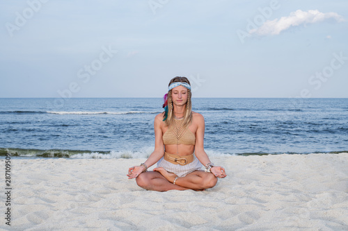 Young woman practicing yoga on the beach. Lotus pose