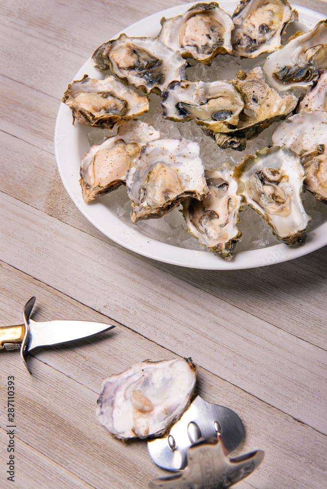 Fresh shucked oysters plate over wood background Fresh shucked oysters plate over wood background