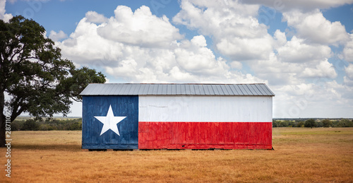 Texas flag painted on old barn. American farmers background, rural scene.