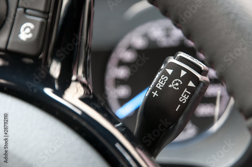 Cruise control switch with blurred speedometer in background