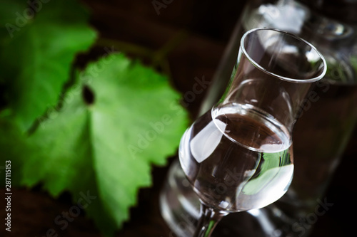 Grape vodka, pisco - traditional Peruvian strong alcoholic drink in elegant shot glasses on vintage wooden table, copy space photo