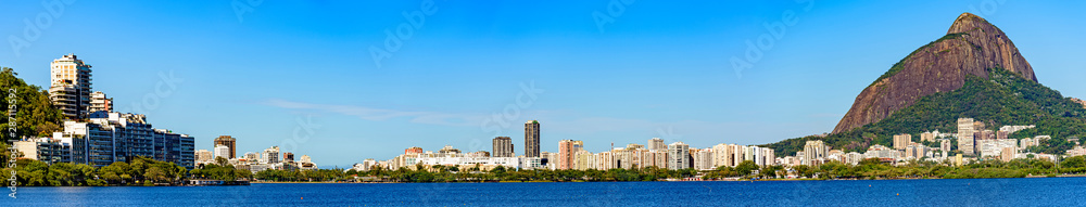 Panoramic image of the Ipanema and Leblon neighborhood and its buildings seen from the lagoon Rodrigo de Freitas with blue sky and calm waters