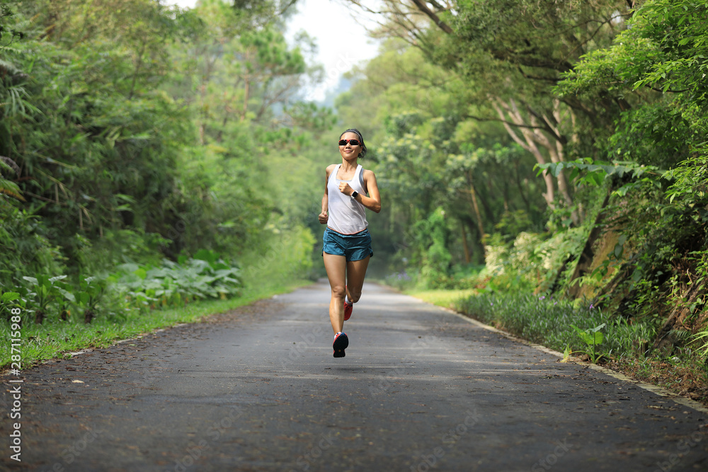 Female runner running at summer park trail . Healthy fitness woman jogging outdoors. Female runner running at summer park trail . Healthy fitness woman jogging outdoors.