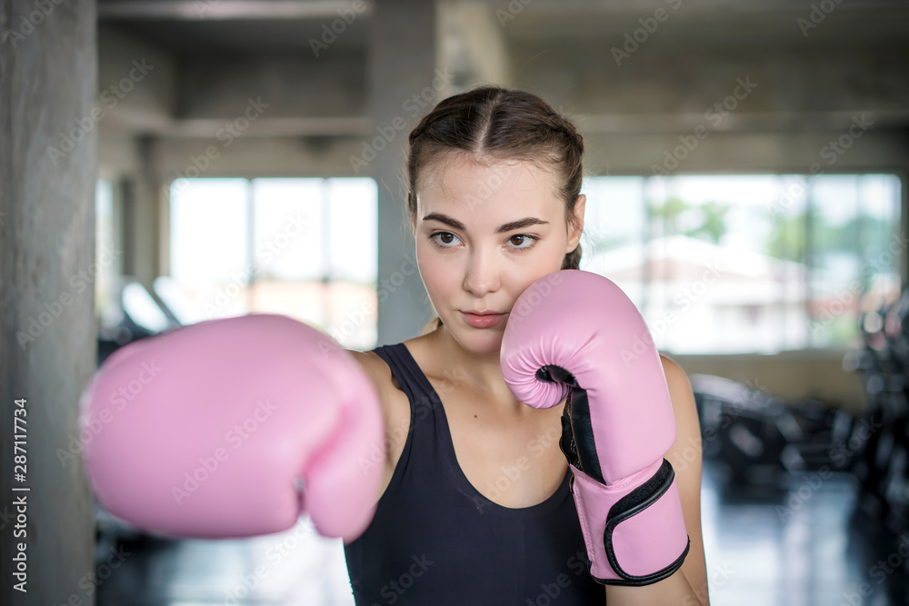 Young beautiful woman with boxing gloves exercise in fitness gym