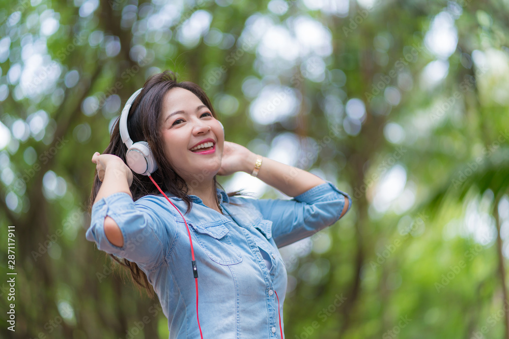 Young beautiful woman enjoying music in the garden listening to music with headphones Young beautiful woman enjoying music in the garden listening to music with headphones