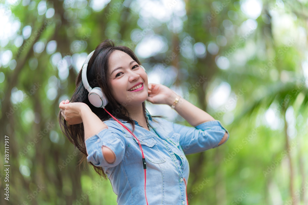 Young beautiful woman enjoying music in the garden listening to music with headphones Young beautiful woman enjoying music in the garden listening to music with headphones