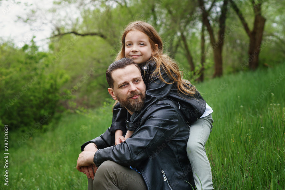 Fashionable happy family walking in the park. Portrait of a loving daughter and a caring father. Time together. Family look. Urban casual outfit. Fashionable happy family walking in the park. Portrait of a loving daughter and a caring father. Time together. Family look. Urban casual outfit.