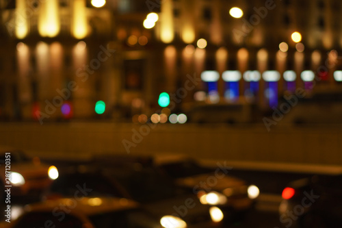 Defocused night city life: cars, people and street lamps. Bokeh urban city background effect. Holidays, sale and retail concept. Design background