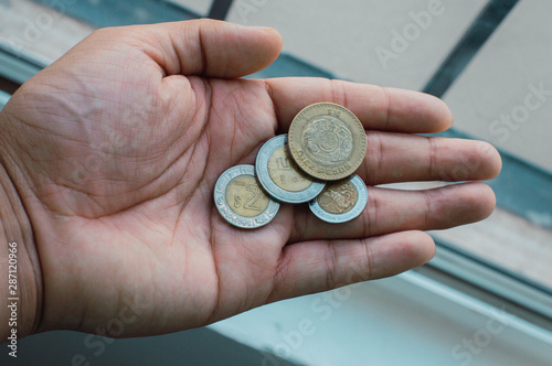 Monedas en la palma de la mano. Pesos mexicanos sobre la mano de hombre adulto.