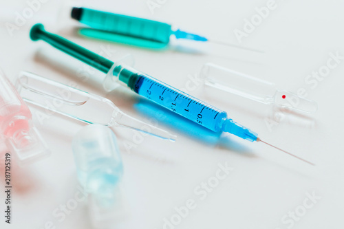  syringes and ampoules with multicolored liquid on a white background.