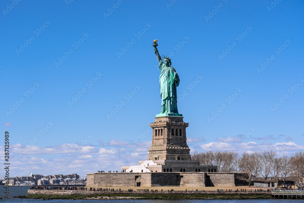 Obraz premium The Statue of Liberty under the blue sky background, Lower Manhattan, New York City, Architecture and building with tourist concept