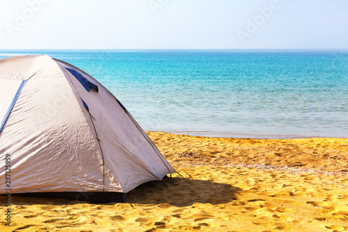 Camping tent on the sand beach against sea horizon.