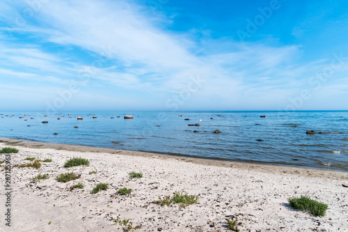 Summer view by a sand beach with rocks in the water