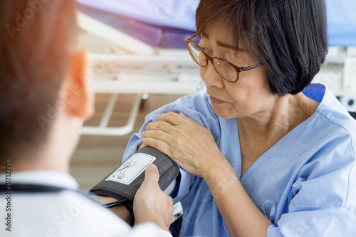 Health care concept; Doctor checking old woman patient arterial blood pressure.