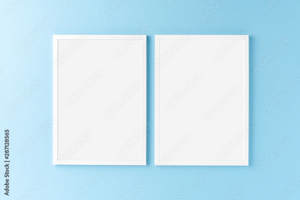 Two white photo frames with copyspace on blue background. Home decoration Two white photo frames with copyspace on blue background. Home decoration
