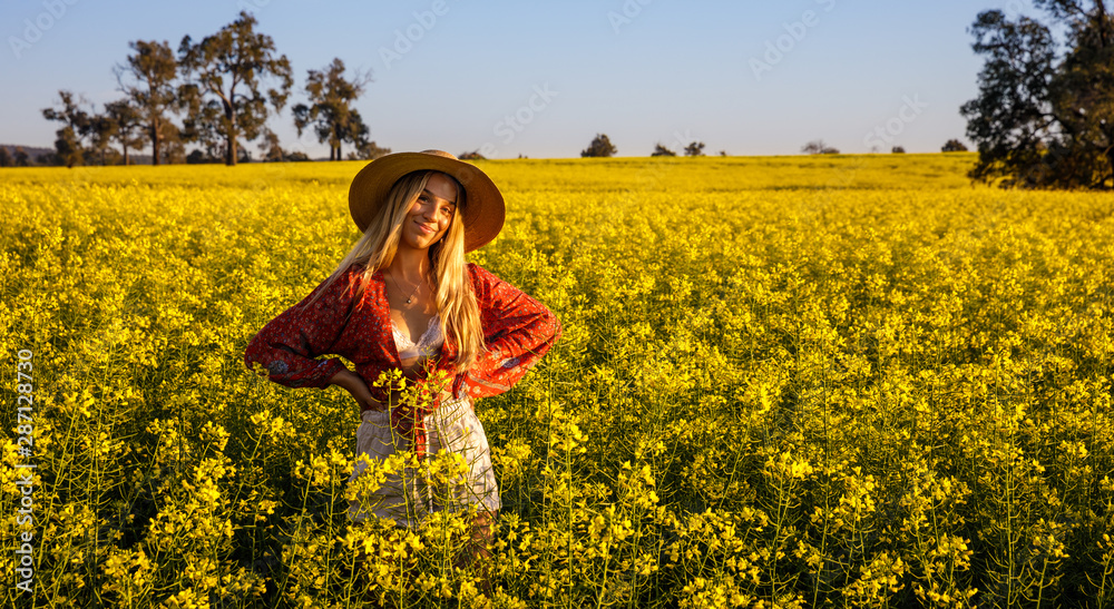 Fototapeta premium Happy young lady with straw hat in yellow Canola Field in Western Australia