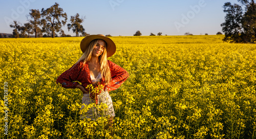 Happy young lady with straw hat in yellow Canola Field in Western Australia photo