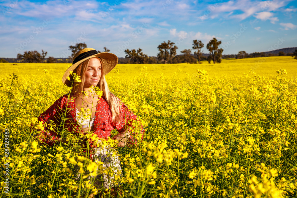Happy young lady with straw hat in yellow Canola Field in Western Australia