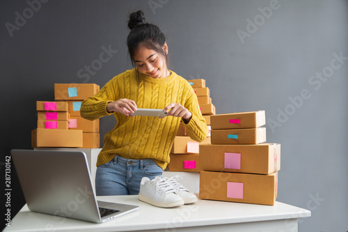 Young women taking photo to shoes with cell telephone or smartphone digital camera for post to sell online on the Internet and preparing pack product box. Selling online ideas concept photo