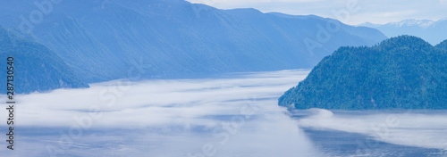 Panoramic view. Morning fog over a mountain lake. Teletskoye lake, Altai, Russia.