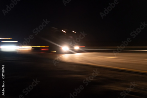 Abstract image with blurry car fragments on a speedway.The cars moves at fast speed at the night. Blurred lights with car on high speed..Speed Traffic-light trails on motorway highway at night, long.