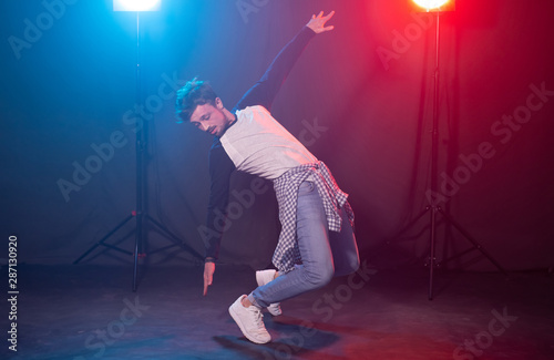 Dance, hip-hop and reggaeton concept - young man dancing over the lights.