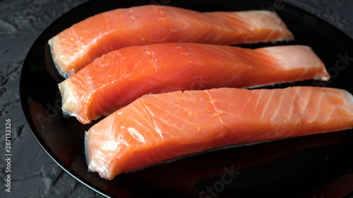 Close up slices of salmon on a black dish. Salted salmon.