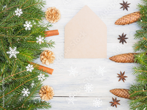 Fir tree branch with cones, cinnamon, anise, envelope, snowflake on white wooden background. Christmas and New Year concept