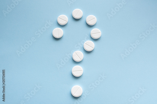 Question mark made of medicine tablets on a blue background. Isolated.