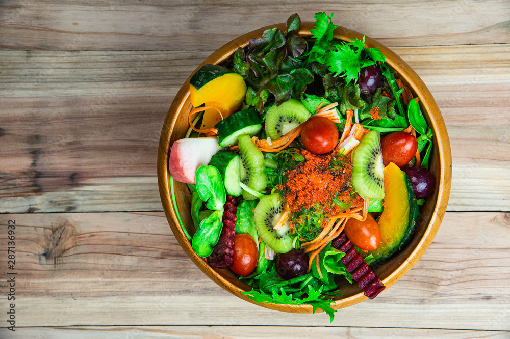 Top view various fresh healthy mixed vegetables salad serving in wooden bowl.