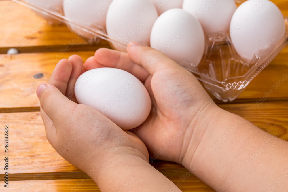木材の背景に子供の両手で卵を抱え持っている生卵 ゆで卵 Stock 写真 Adobe Stock
