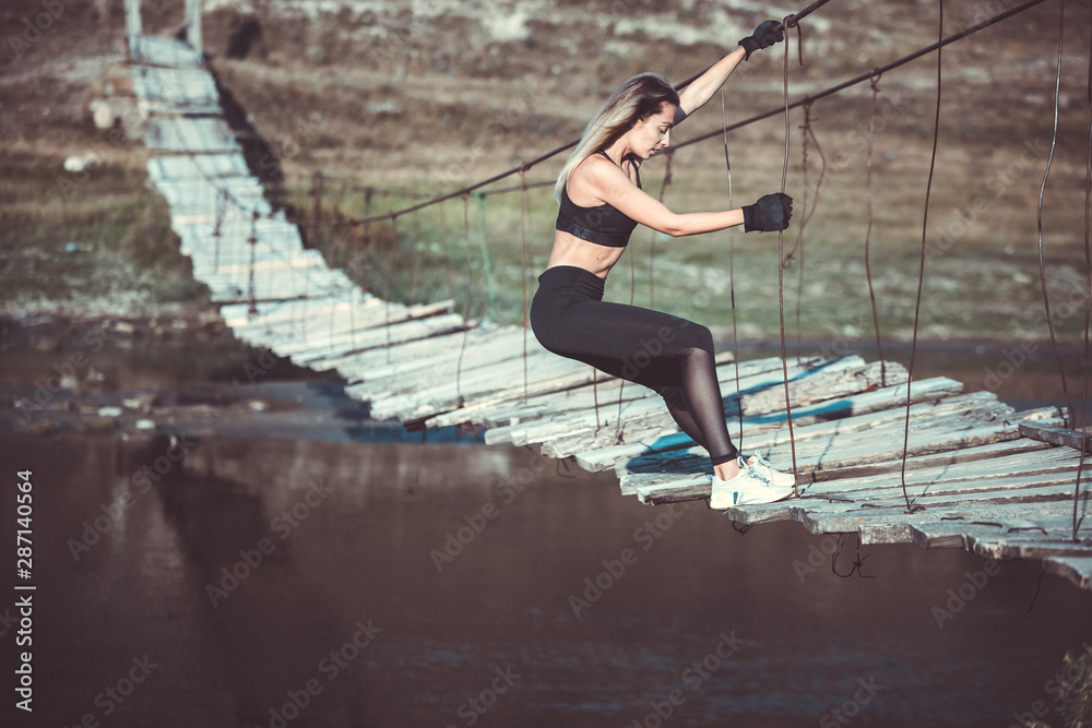 Attractive young sporty woman is working outside. Cross fit training. Muscular woman. Young, fit and beautiful girl in sporty swimsuit. Sport, diet, health and beauty concept. Young woman in black spo