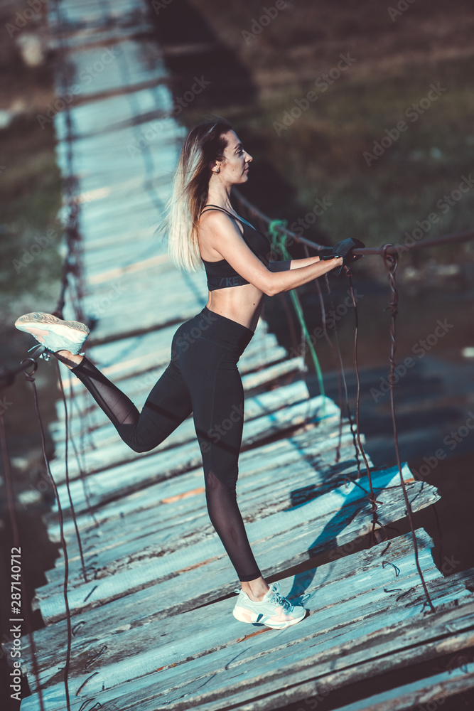 Attractive young sporty woman is working outside. Cross fit training. Muscular woman. Young, fit and beautiful girl in sporty swimsuit. Sport, diet, health and beauty concept. Young woman in black spo Attractive young sporty woman is working outside. Cross fit training. Muscular woman. Young, fit and beautiful girl in sporty swimsuit. Sport, diet, health and beauty concept. Young woman in black spo
