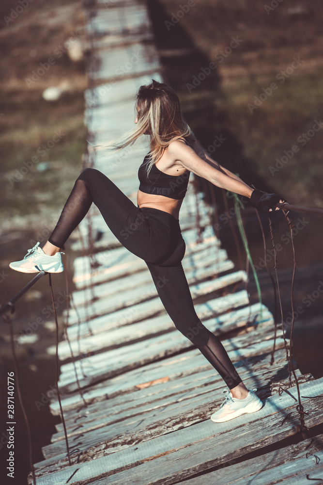 Attractive young sporty woman is working outside. Cross fit training. Muscular woman. Young, fit and beautiful girl in sporty swimsuit. Sport, diet, health and beauty concept. Young woman in black spo Attractive young sporty woman is working outside. Cross fit training. Muscular woman. Young, fit and beautiful girl in sporty swimsuit. Sport, diet, health and beauty concept. Young woman in black spo