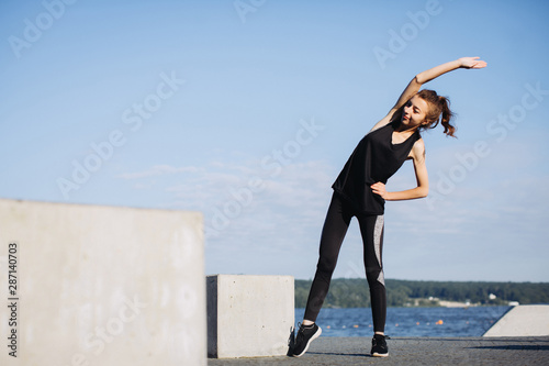 A young girl exercising by the lake