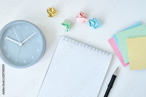 Gray round alarm clock colorful sticky notes and notebook on a white background, top view