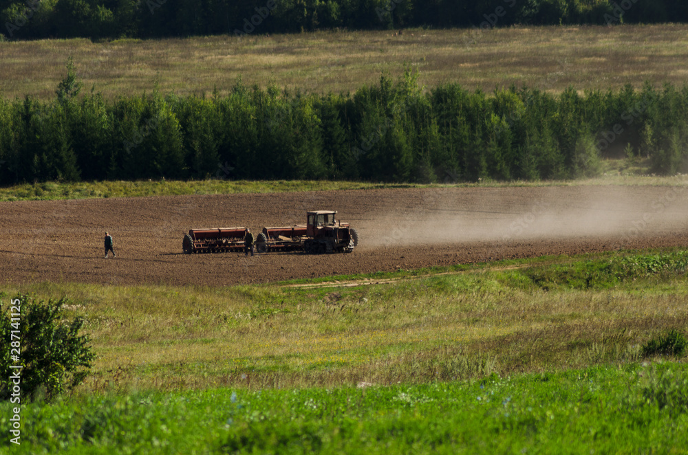Fototapeta premium tractor cultivates field, agriculture in countryside