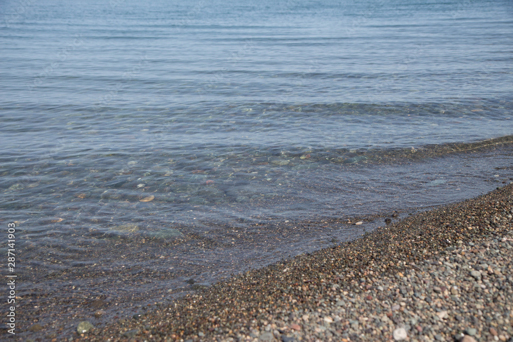 Wet stones on the sea shore. transparent waves with foam, on a warm Wet stones on the sea shore. transparent waves with foam, on a warm