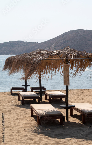 Fototapeta Naklejka Na Ścianę i Meble -  Greece the island of Ios. The port beach of Yailos. Summer time. Relaxation, sunbeds and sunbathing. Rows of sunbeds and parasols on the sandy beach. Time to rest and recharge batteries.