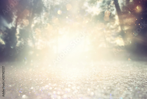 Abstract background of light burst among trees and glitter golden bokeh lights