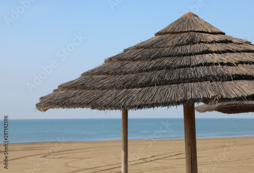 Fototapeta Naklejka Na Ścianę i Meble -  huge straw umbrella in the sunny deserted beach
