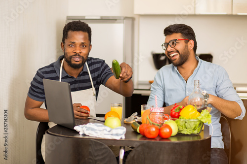 Two man using laptop in kitchen